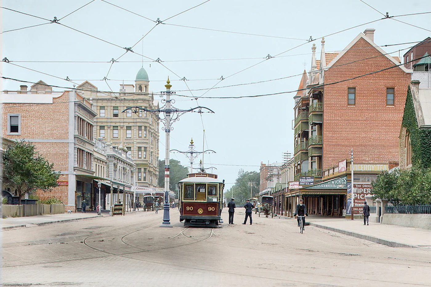 Pulteney Street in 1913, looking south from North Terrace: an electric tram in the middle of a wide unpaved street, overhead wires, a cyclist, pedestrians, and the Ruthven Mansions on the right.